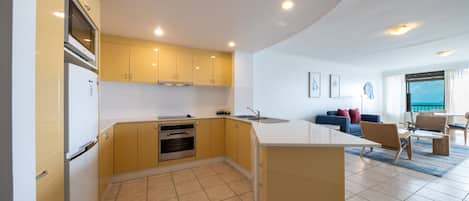 A modern kitchen with yellow cabinets, a built-in oven, and a large island with a sink.