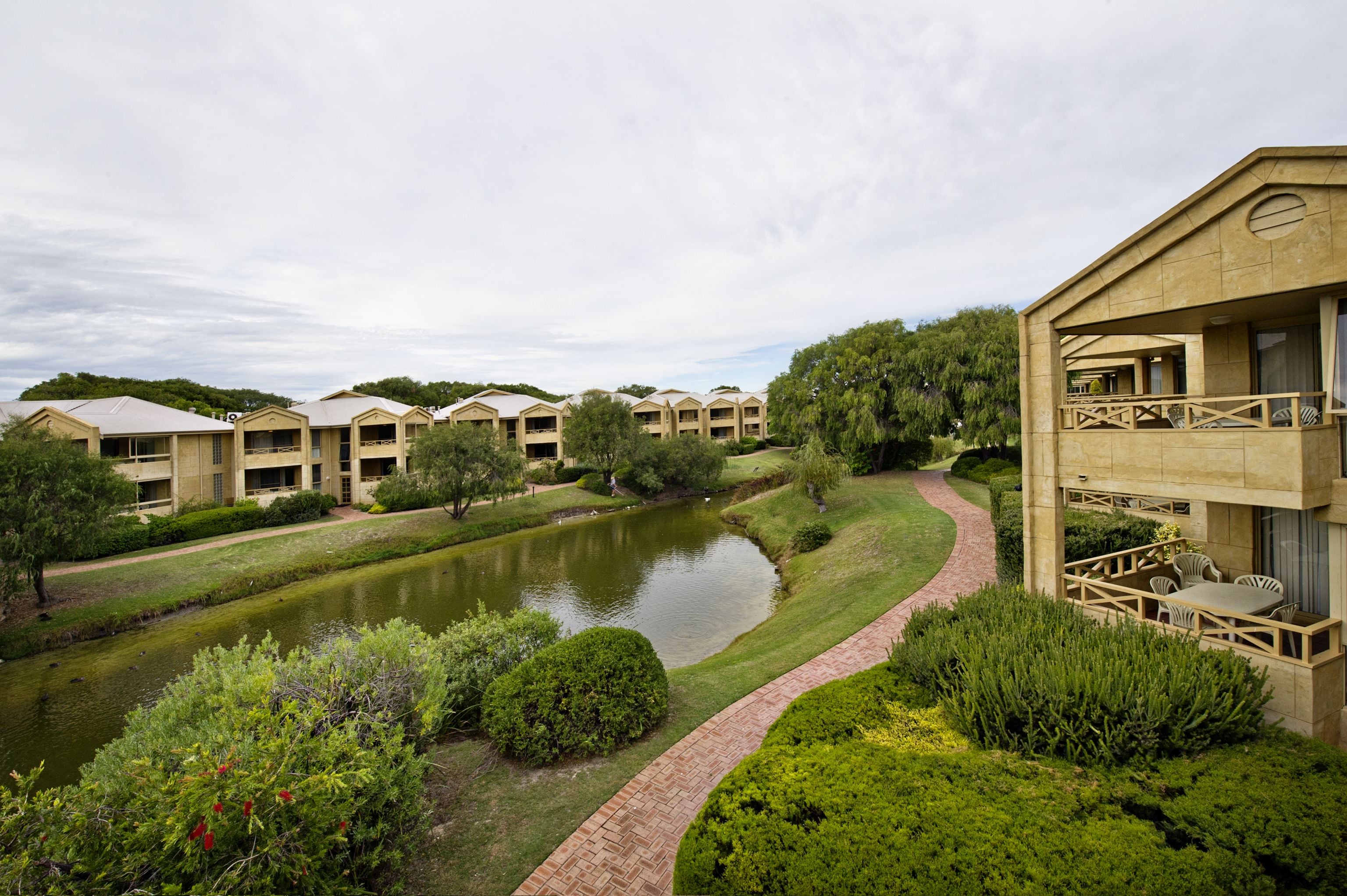 A hotel with multiple buildings, a pond, and well-maintained landscaping.