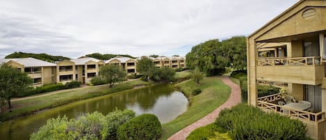 A hotel with multiple buildings, a pond, and well-maintained landscaping.