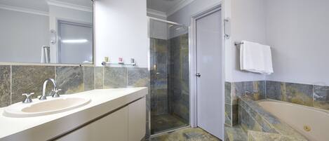 A modern bathroom with a large sink, a glass-enclosed shower, and a bathtub.