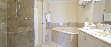 Un baño moderno con ducha de vidrio, bañera independiente y tocador con lavamanos y espejo.