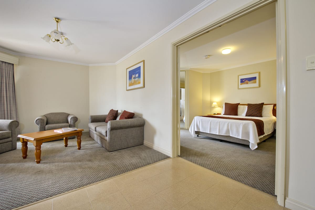 Una habitación de hotel con una cama, un sofá, una mesita y una silla.