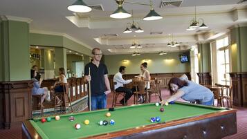 A pool table in a room with green walls and wooden furniture.