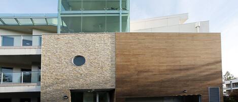 Un edificio moderno con fachada de piedra, sección de madera y nivel superior de vidrio.