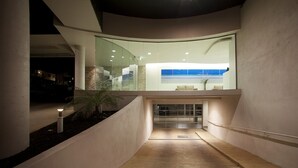 Un interior moderno con un muro de vidrio curvo, una escalera y vistas al cielo.