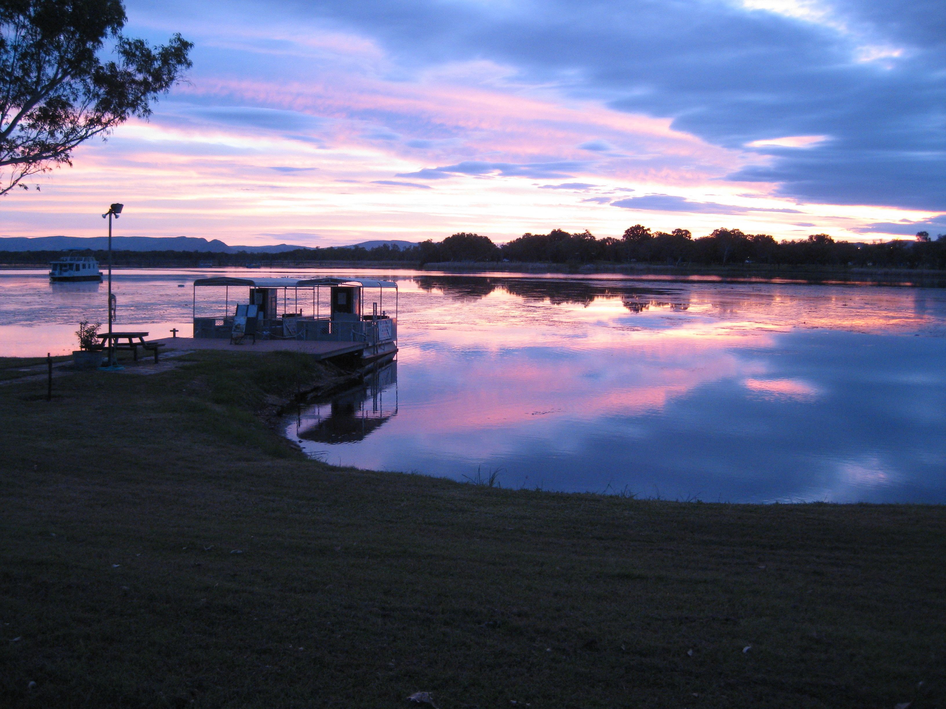 A lakeside dock with a covered seating area and a boat.