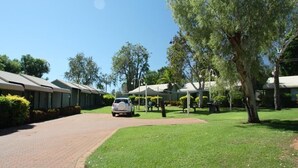 A row of modern, single-story buildings with a paved driveway leading to a parking area. - Lily Lagoon Resort (Kununurra)