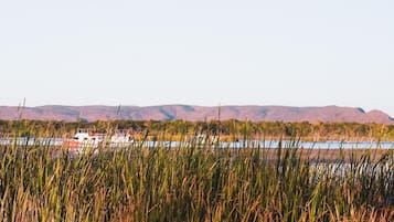 Un paysage comprenant un plan d’eau, un bateau et des collines à l’horizon.