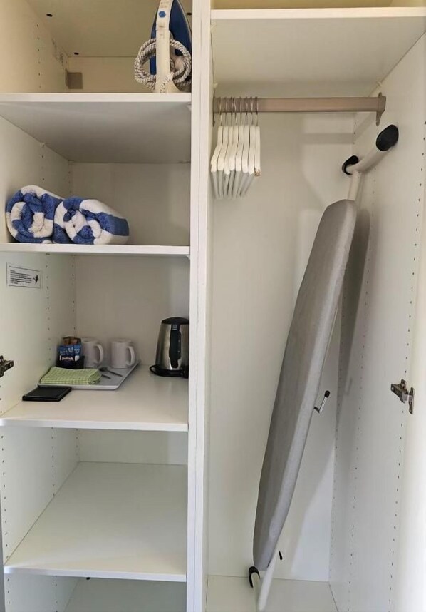 Un armario con estantes, una percha y una puerta con barra para toallas.