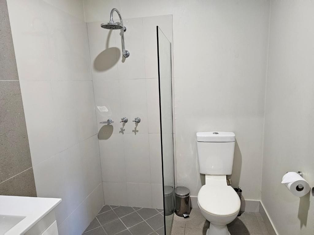 Un baño con ducha acristalada, inodoro y lavamanos.