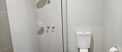 Un baño con ducha acristalada, inodoro y lavamanos.
