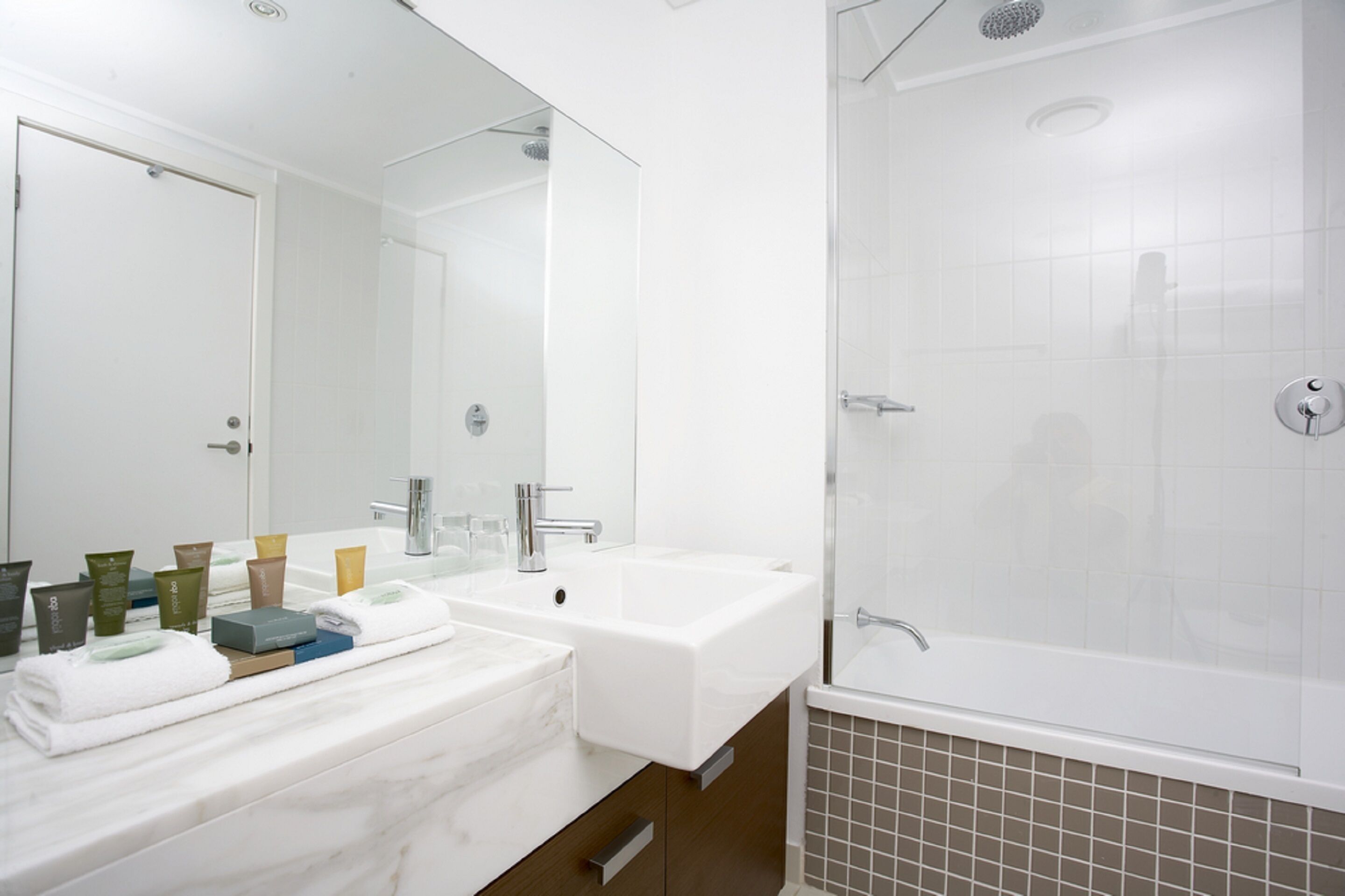 A modern bathroom with two sinks, a large mirror, and a walk-in shower.