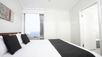 Une chambre d’hôtel moderne avec un grand lit, une fenêtre donnant sur un beau paysage et une porte menant à la salle de bain.