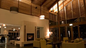 A spacious lobby with a high ceiling, a fireplace, comfortable seating, and large windows.