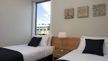 Une chambre d’hôtel avec deux lits, une fenêtre et trois œuvres d’art accrochées au mur.