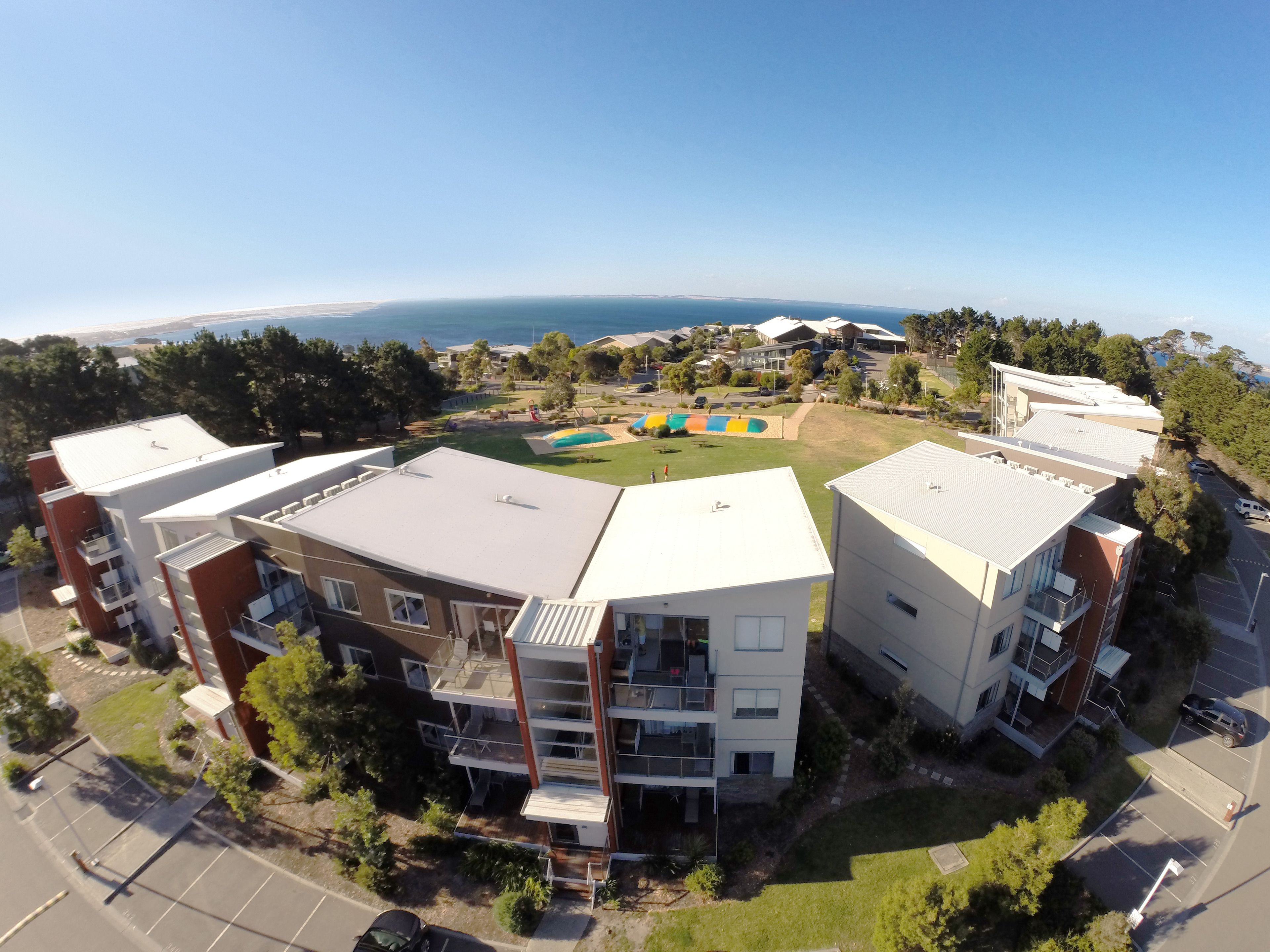 A modern apartment complex with multiple buildings, a playground, and a parking area.
