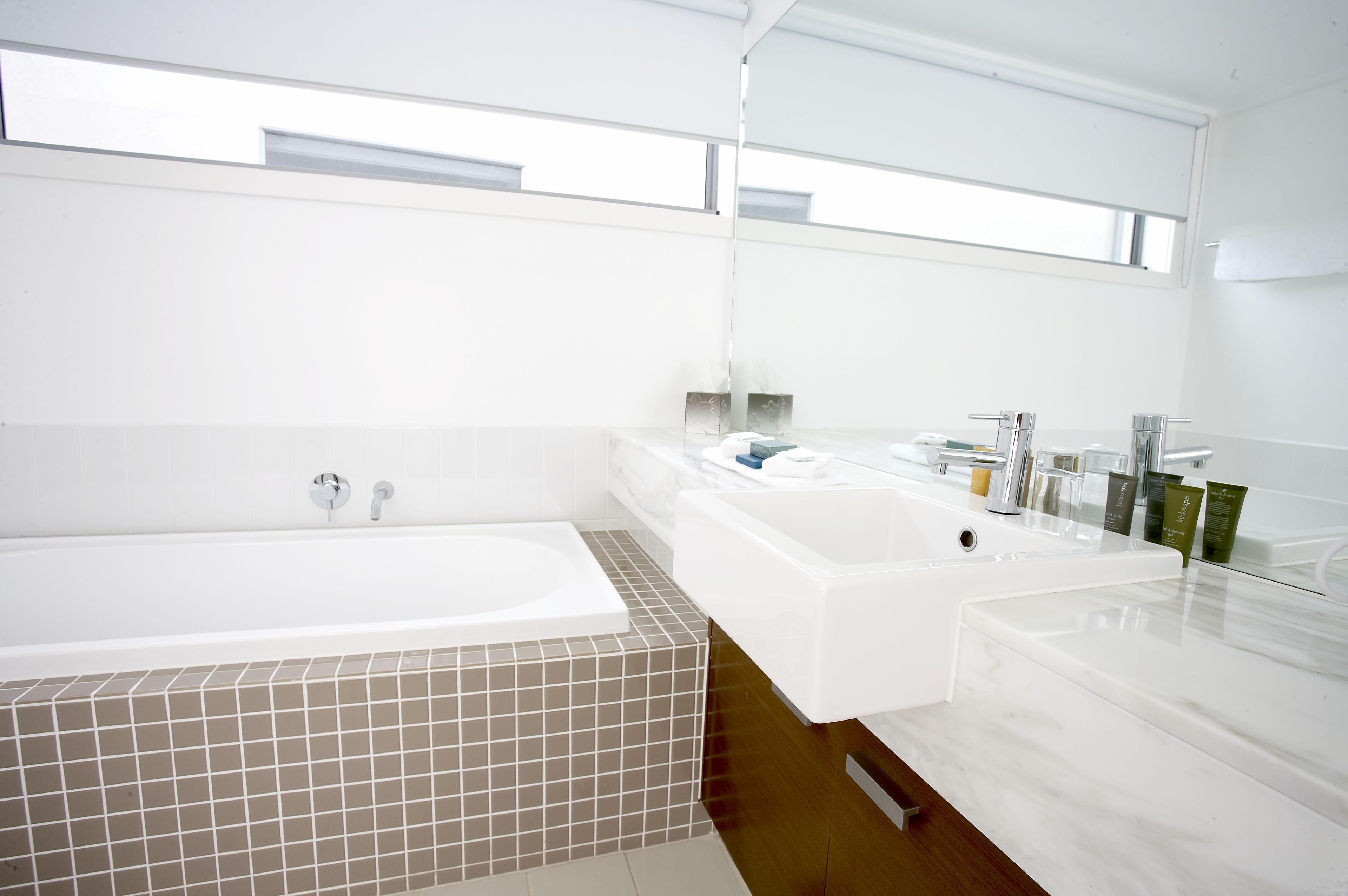 A modern bathroom with a large bathtub, a double sink vanity, and a large mirror.
