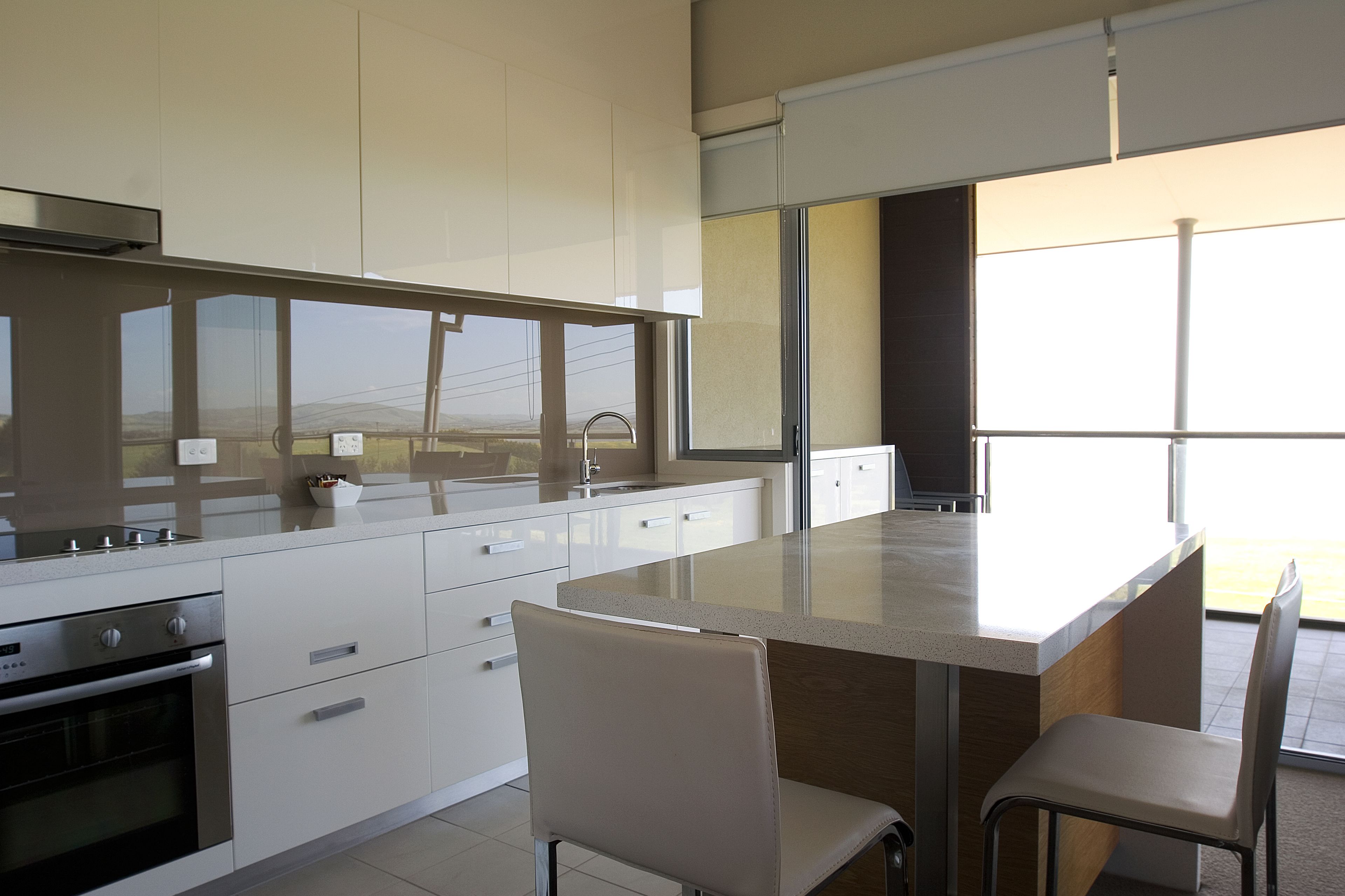 A modern kitchen with white cabinetry, a large island, and a view of the outdoors.