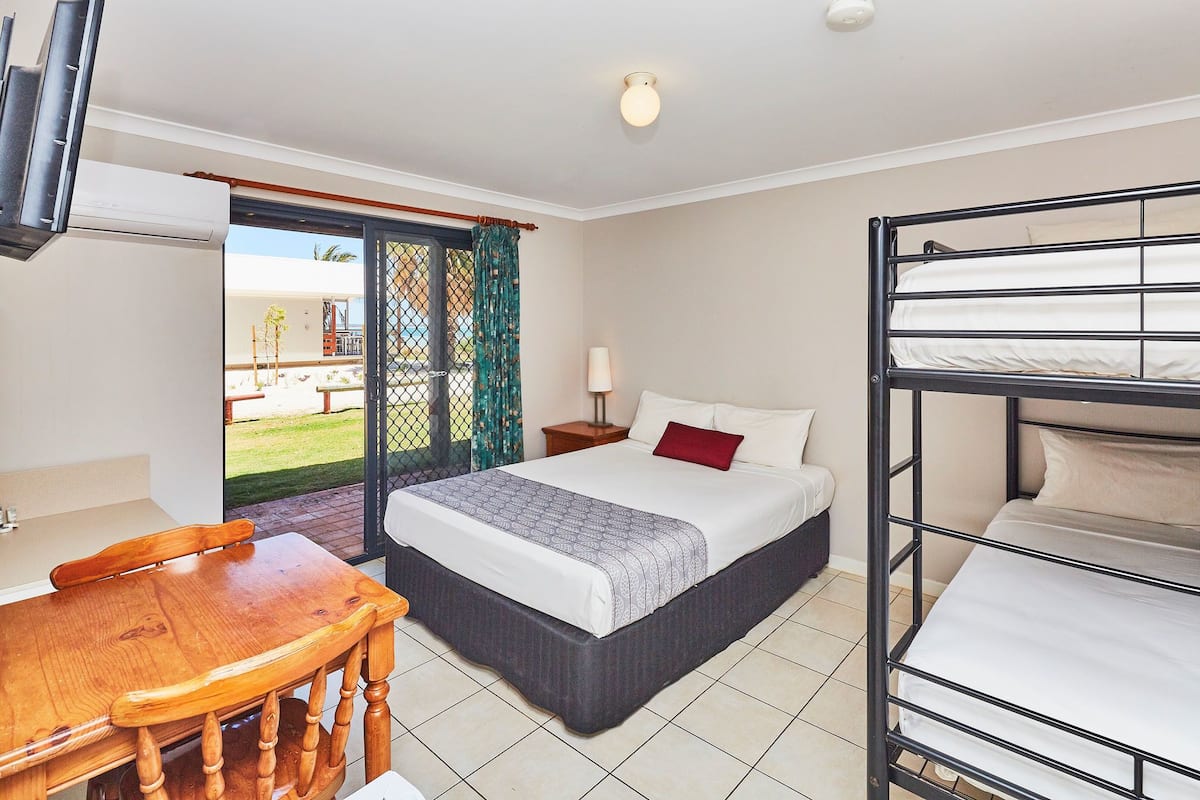 Un dormitorio con una cama litera, una cama individual, una mesa de madera y una silla.