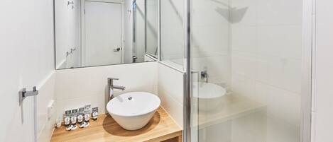 Een moderne badkamer met een douchecabine van glas, een houten wastafelmeubel en een grote spiegel.