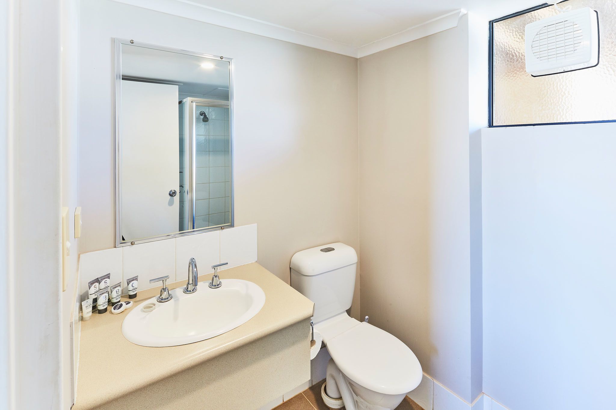 A bathroom with a white sink, mirror, and toilet.