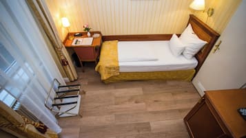 Ein Hotelzimmer mit Bett, Nachttisch, Lampe und kleinem Schreibtisch mit Stuhl.