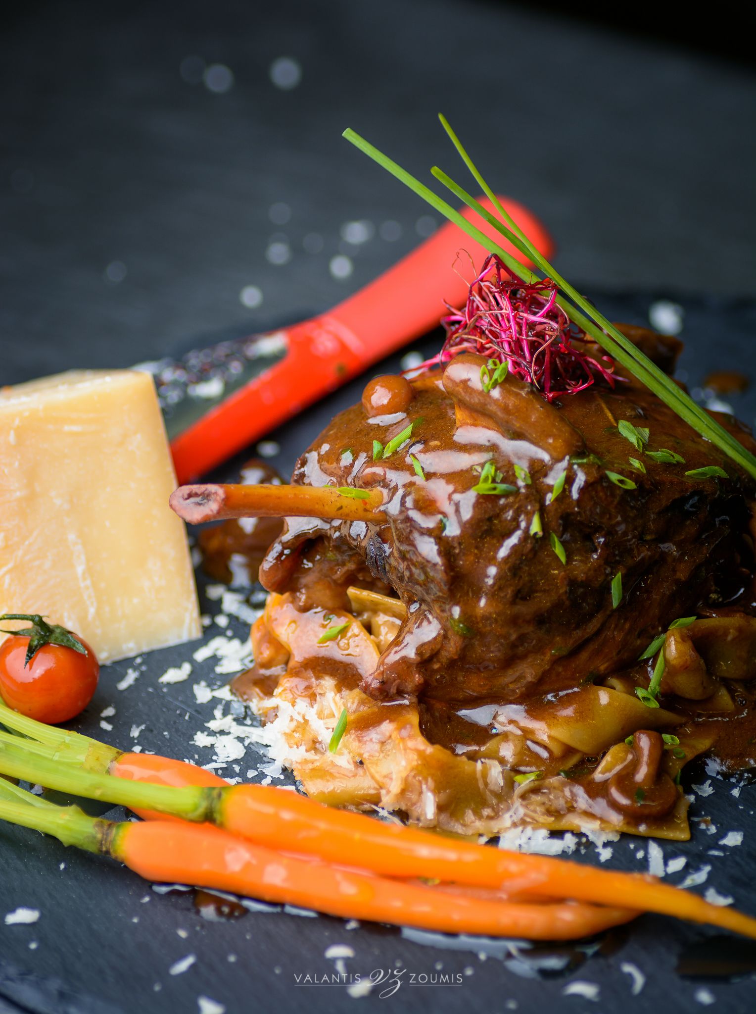 Un plato con carne, verduras y queso sobre una losa.