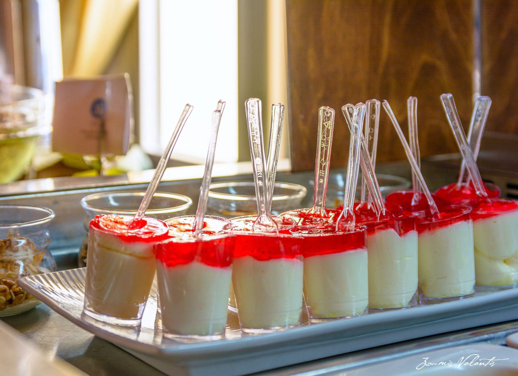 A tray of layered desserts with clear plastic straws.