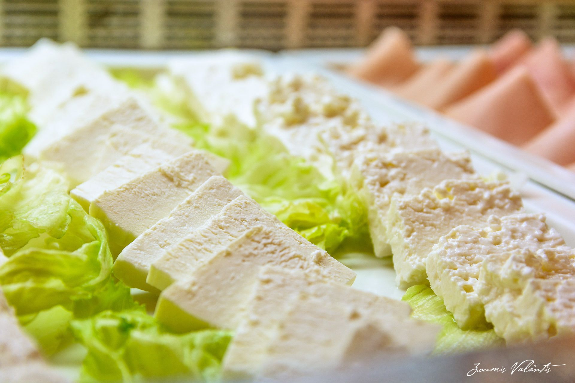 A close-up of a food display with tofu and a creamy sauce on a bed of lettuce.