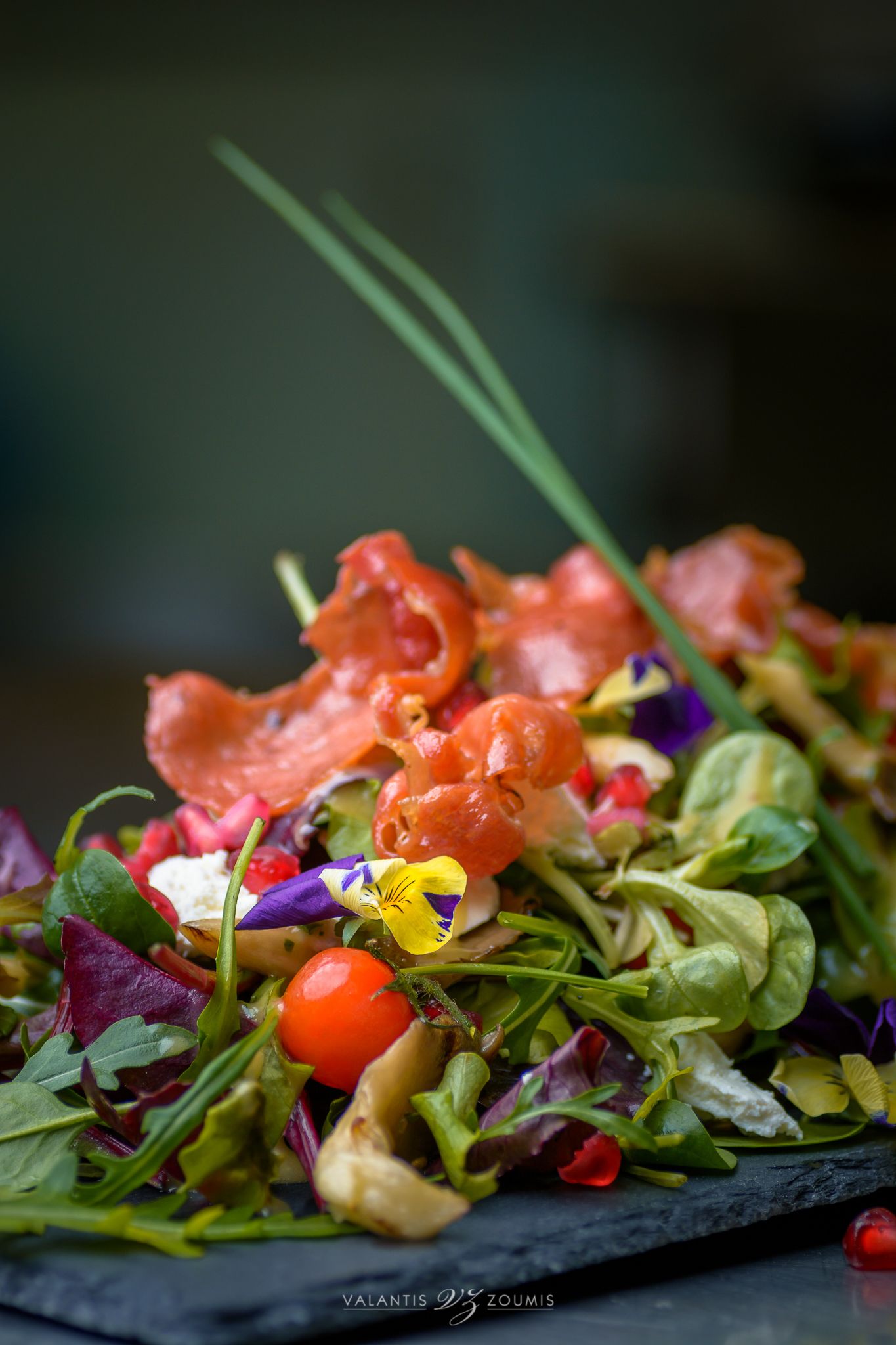 A close-up of a colorful salad with various greens, cherry tomatoes, and other vegetables.