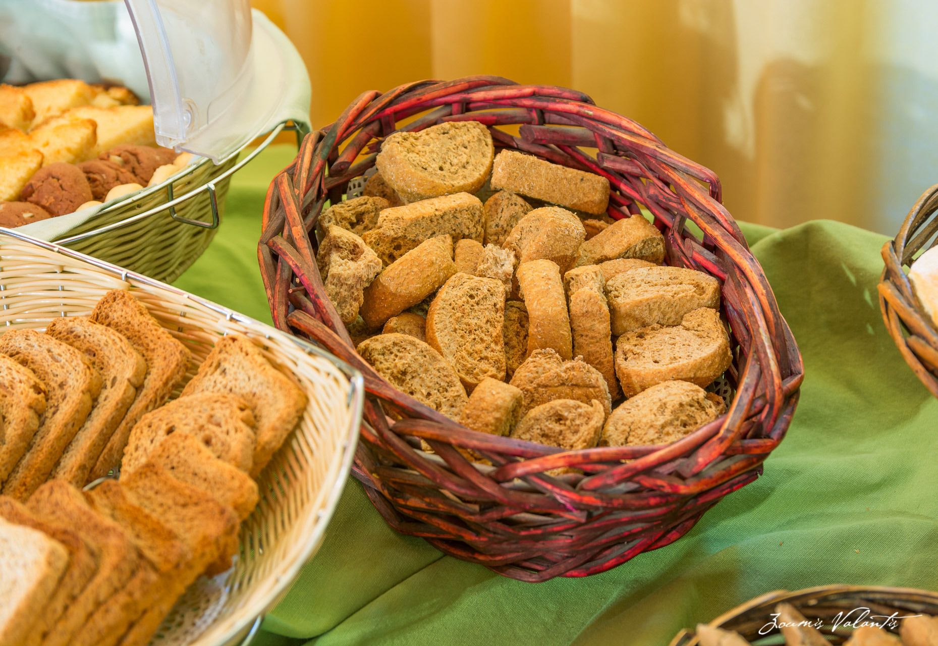 A variety of breads and cookies in baskets on a table.