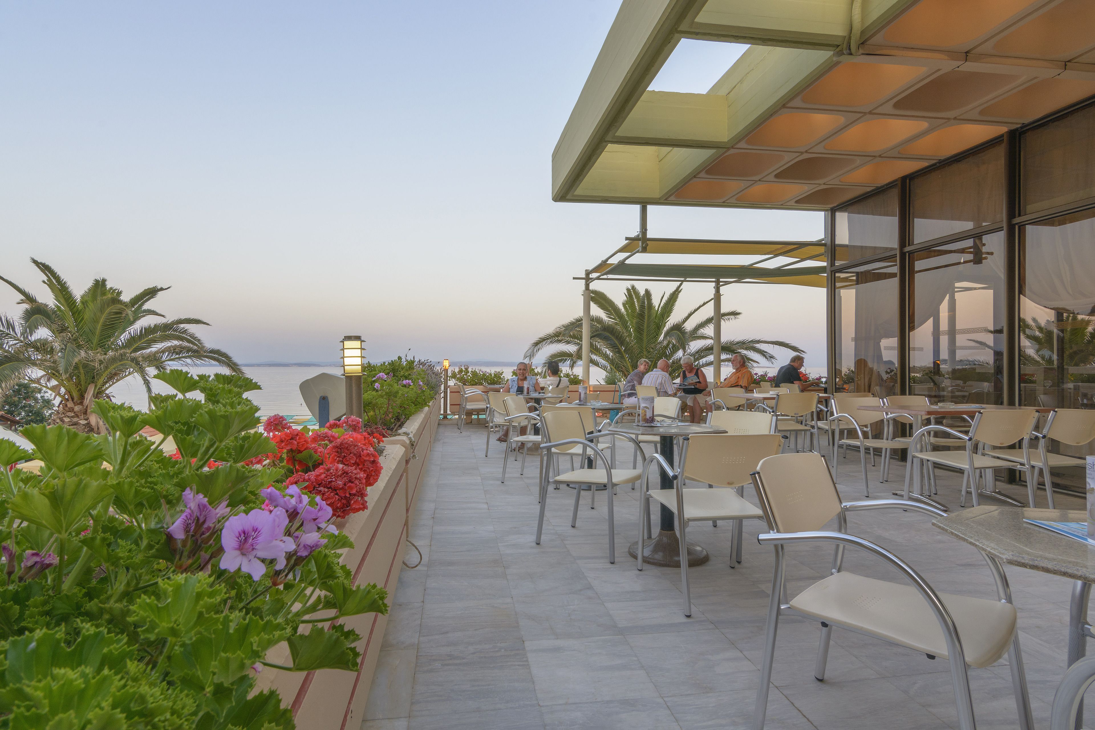 An outdoor patio with tables and chairs, overlooking a body of water.