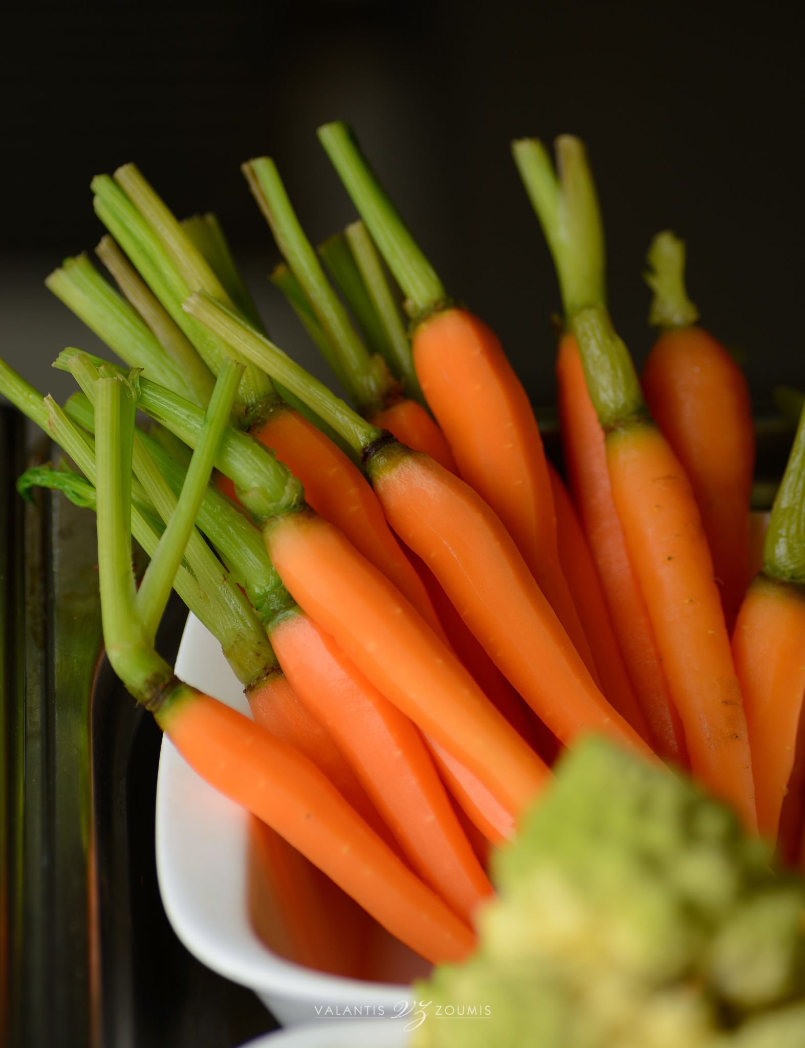 Un bol de carottes fraîches avec leurs fanes vertes.