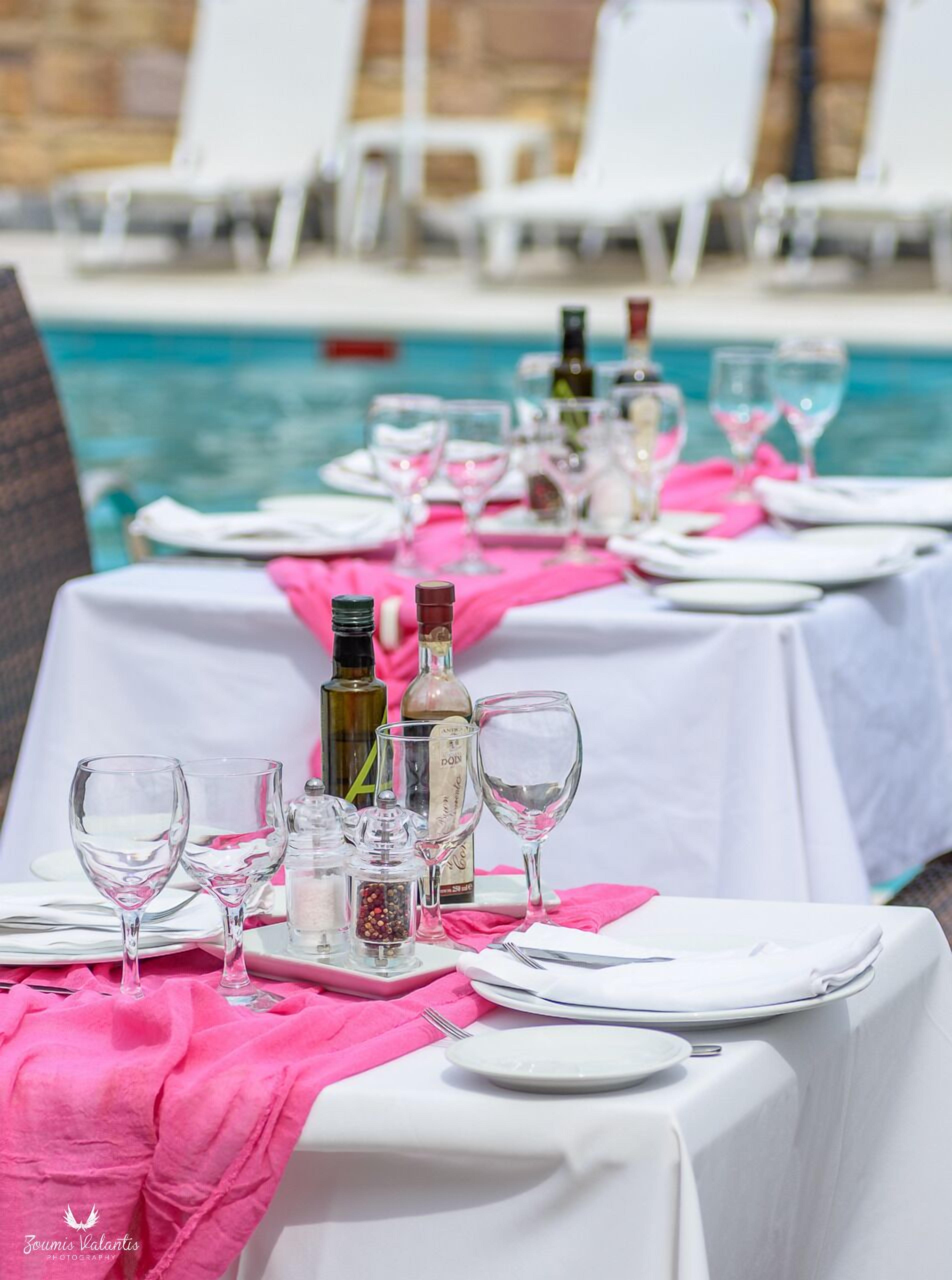 Una mesa de comedor dispuesta para una comida, con copas de vino, botellas y saleros y pimenteros.