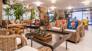 A cozy lounge area with wicker furniture, a wooden coffee table, and various potted plants. - Capo Peloro Resort - Adults Only (Messina)