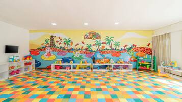 A brightly colored playroom with a checkered floor, shelves with toys, and a mural depicting a park scene.