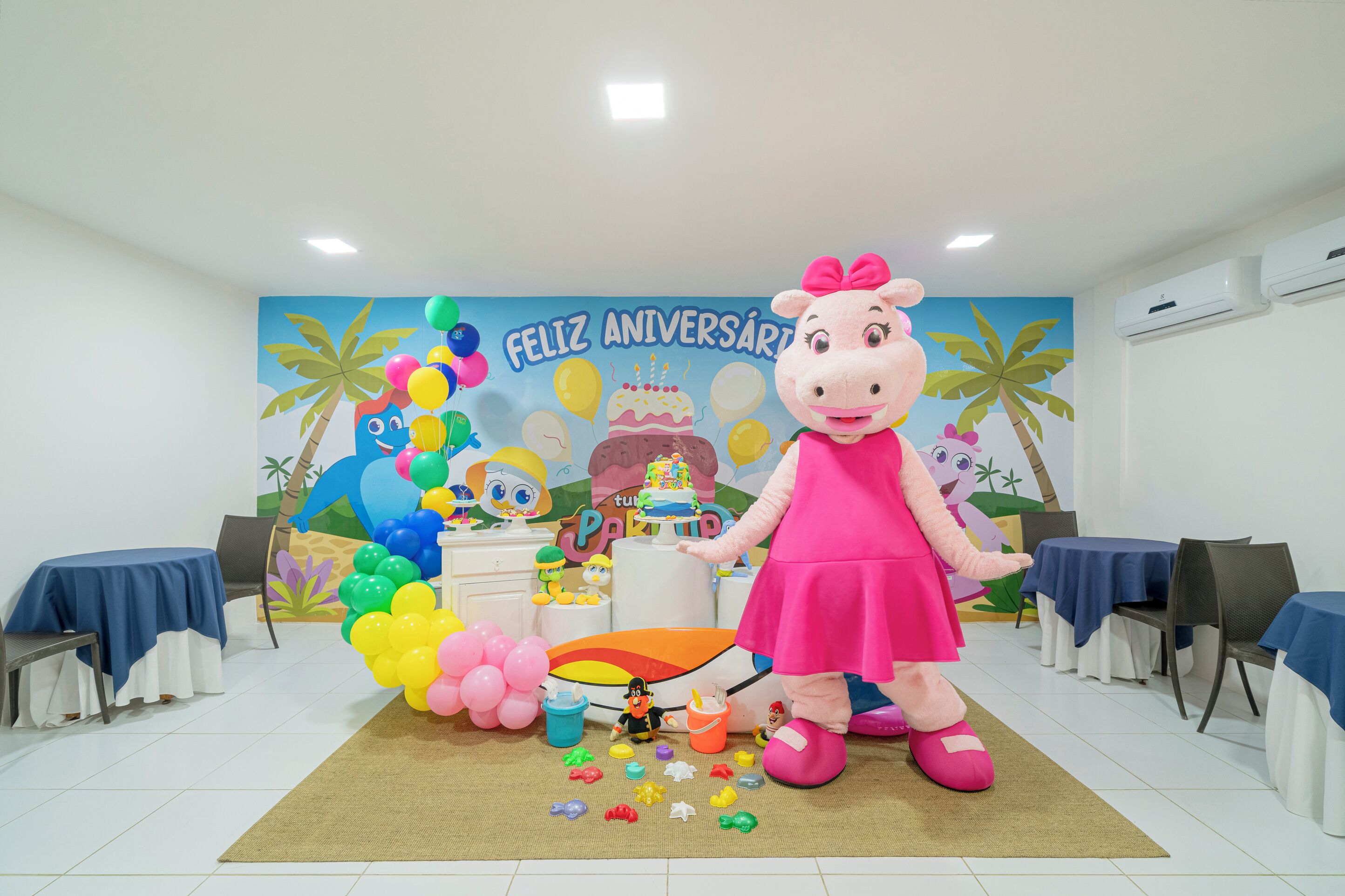 Una habitación decorada para una fiesta de cumpleaños, con un personaje de caricatura grande, globos y un pastel.