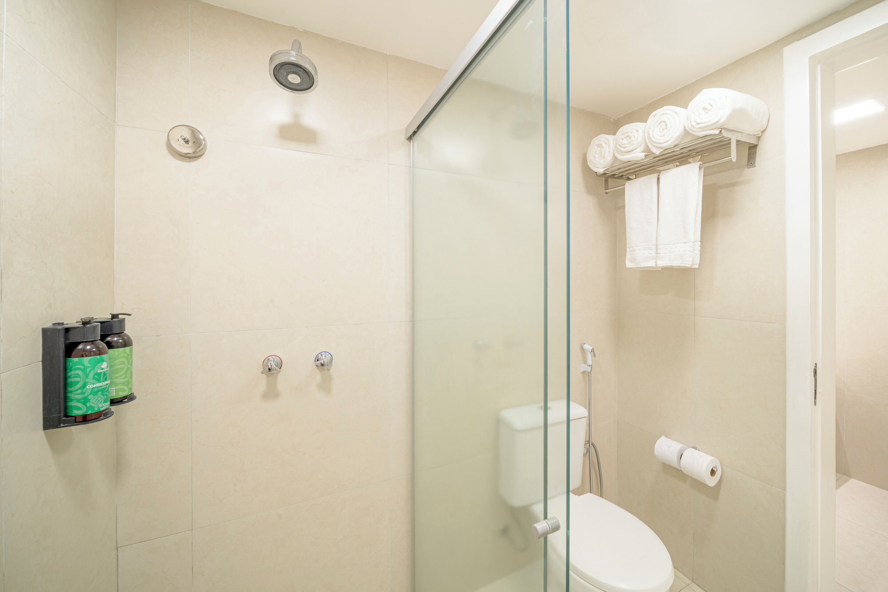 A modern bathroom with a glass-enclosed shower, a toilet, and a towel rack with neatly rolled towels.