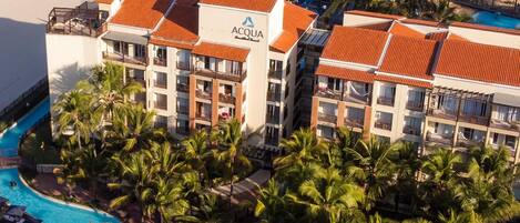 A resort with a large pool, multiple buildings, and a beach.