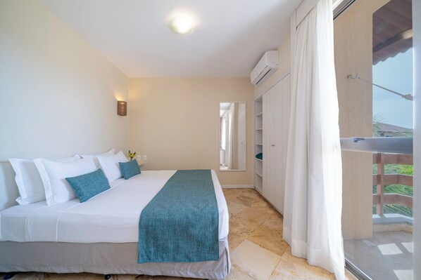 A bedroom with a bed, a nightstand, a window with curtains, and a balcony with a railing. - Beach Park Suites Resort (Aquiraz)