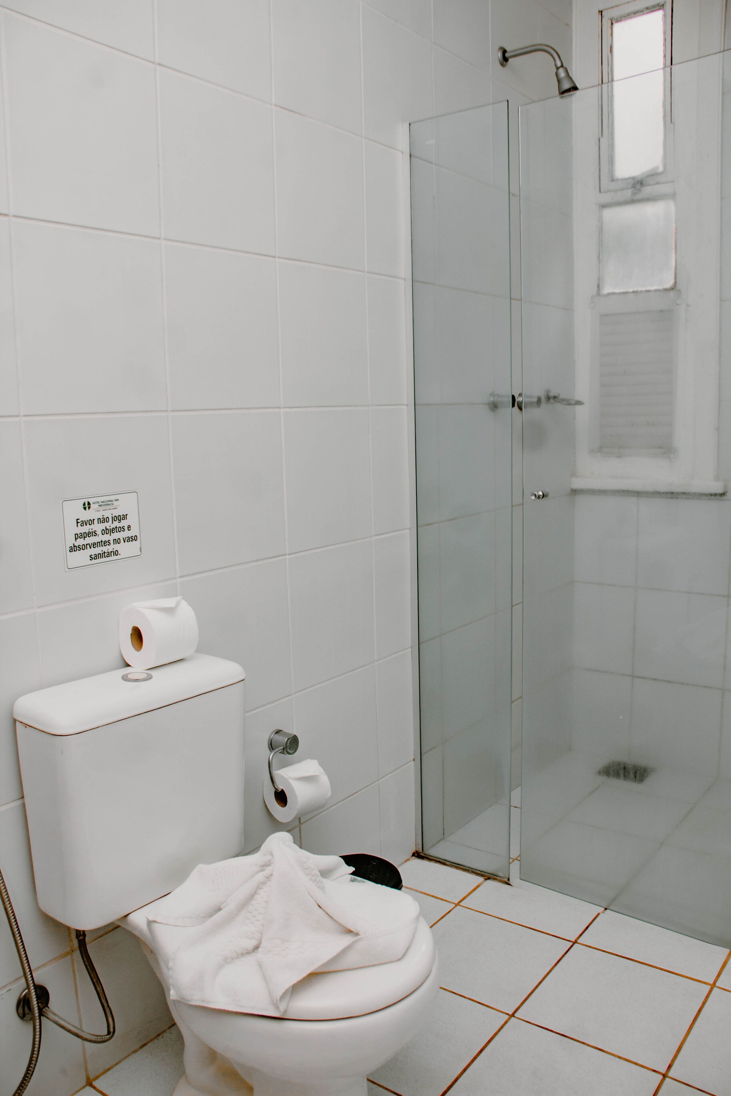 A bathroom with a toilet, a glass shower enclosure, and a sign on the wall.