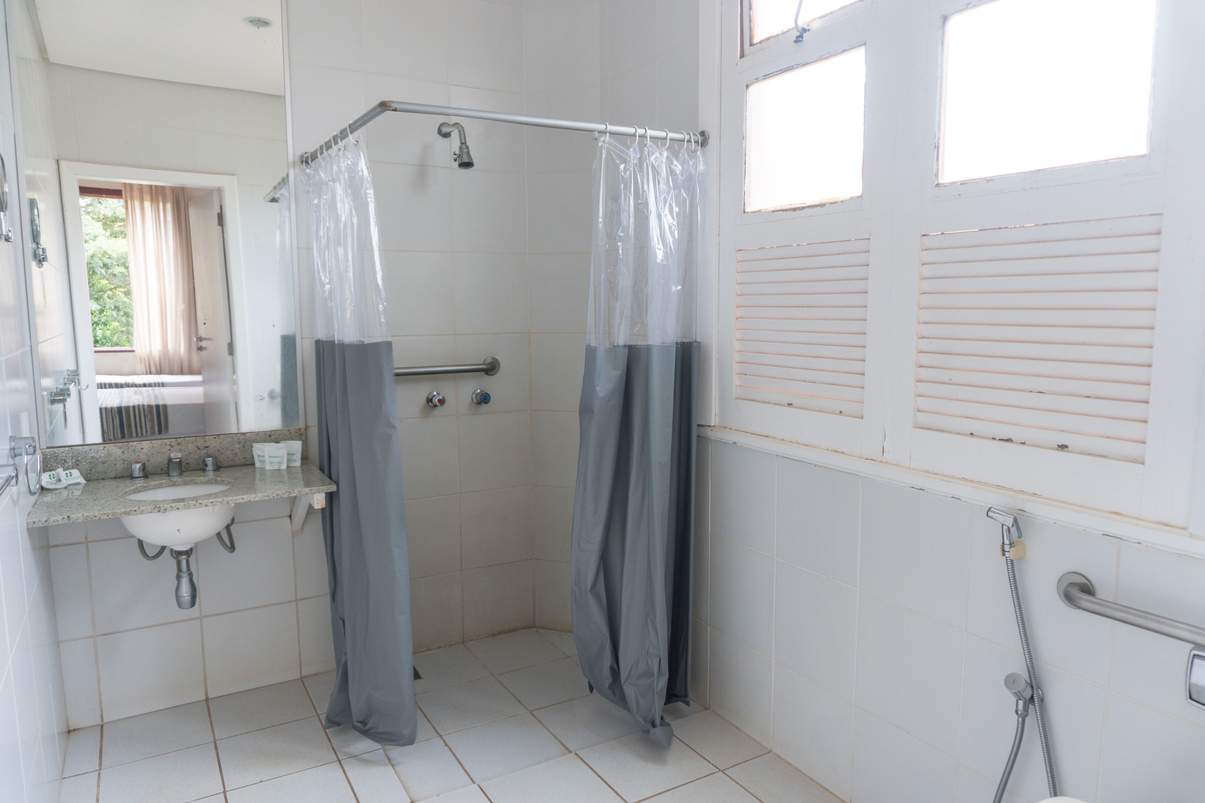 Ein Badezimmer mit Dusche, Waschbecken und Fenster.