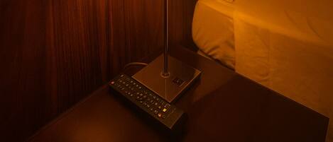 Ein Hotelzimmer mit Holz-Kopfteil, einer Nachttischlampe, einer Fernbedienung und einem Bett mit weißer Bettwäsche.