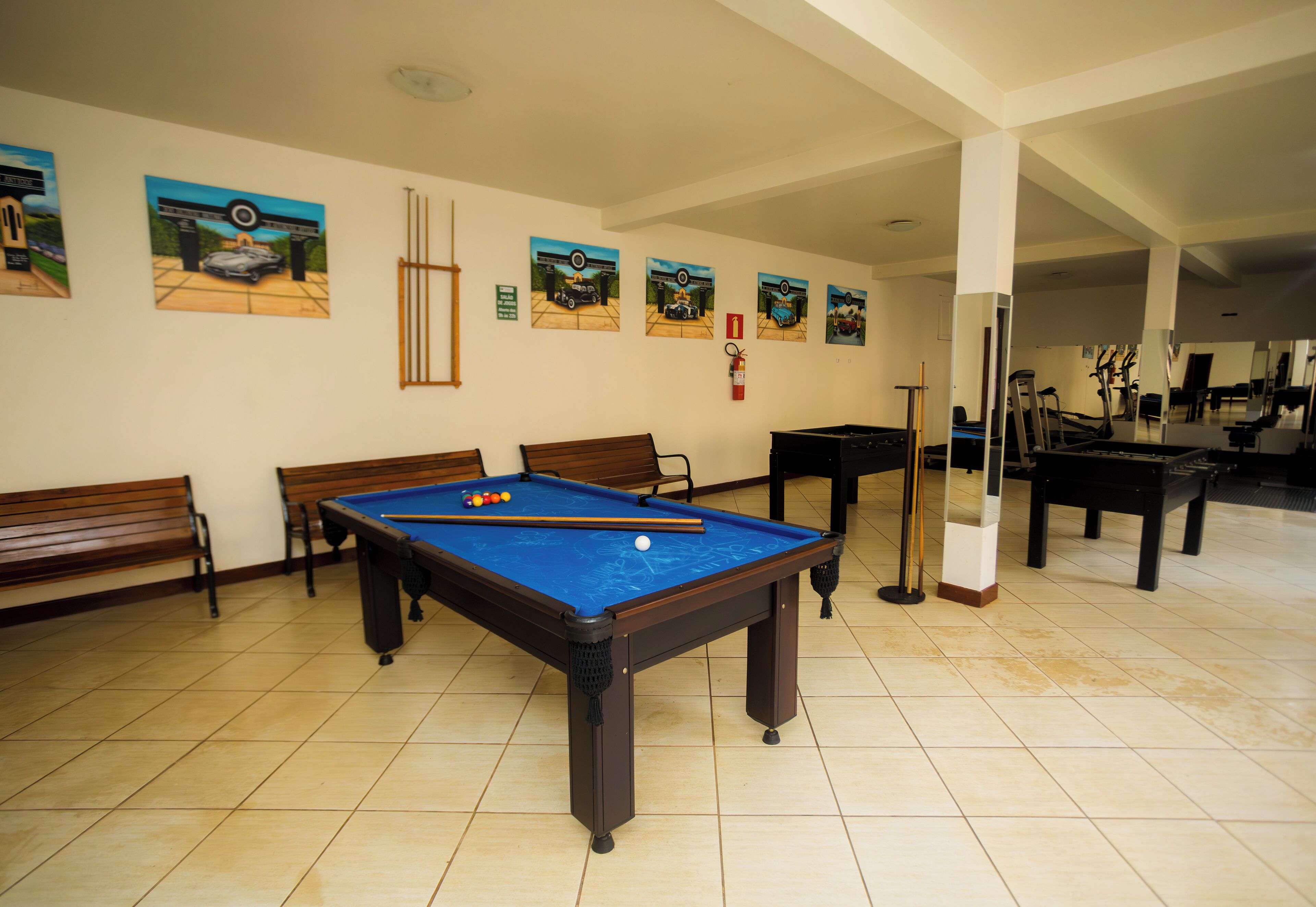 A pool table with billiard balls, a fire extinguisher, and a mirror reflecting the room.