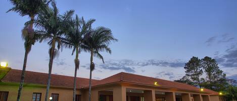 A hotel with a red-tiled roof, palm trees, and a paved entrance area.