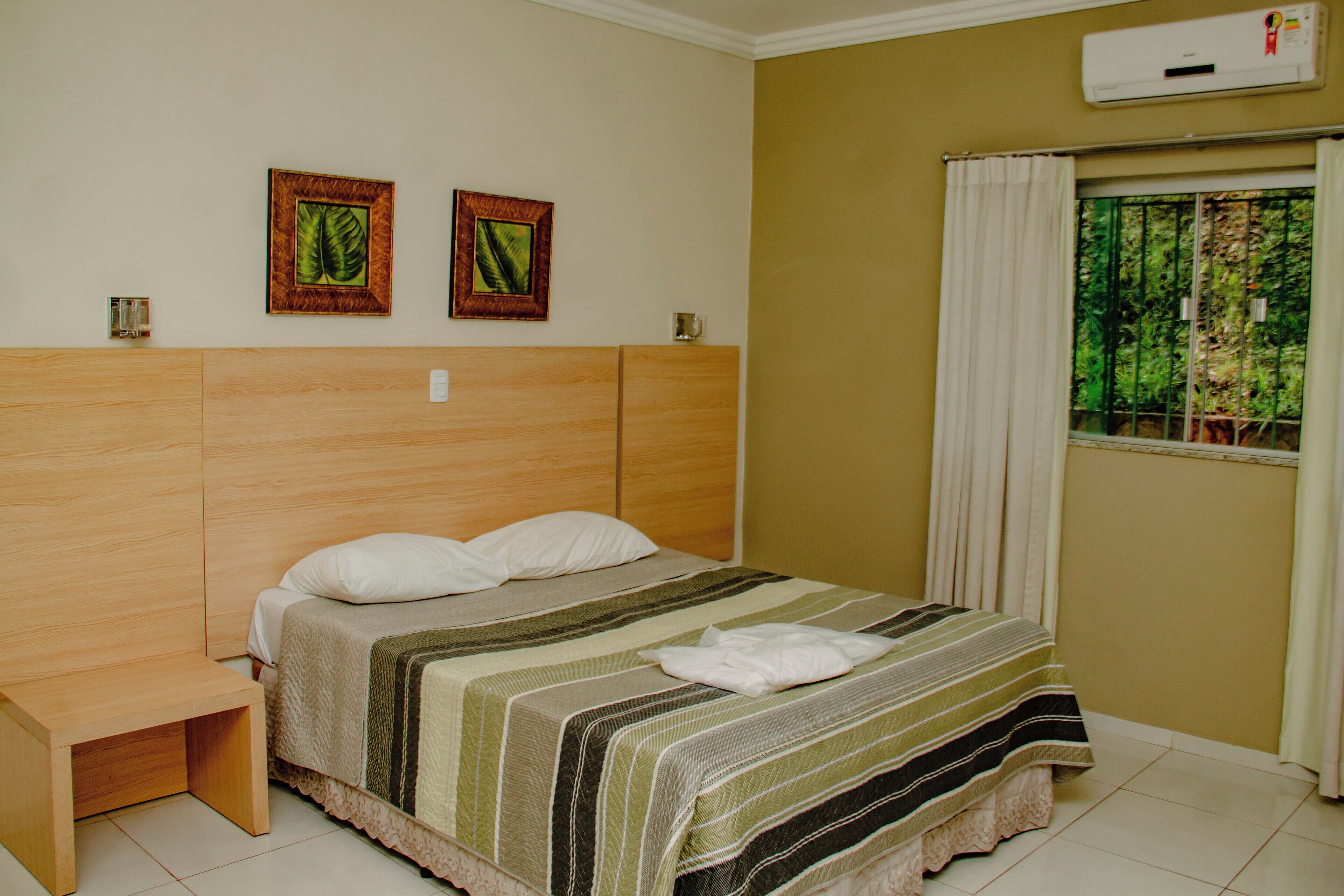 A neatly made bed with a striped bedspread, two pillows, and a folded towel. There are two framed pictures on the wall above the bed.