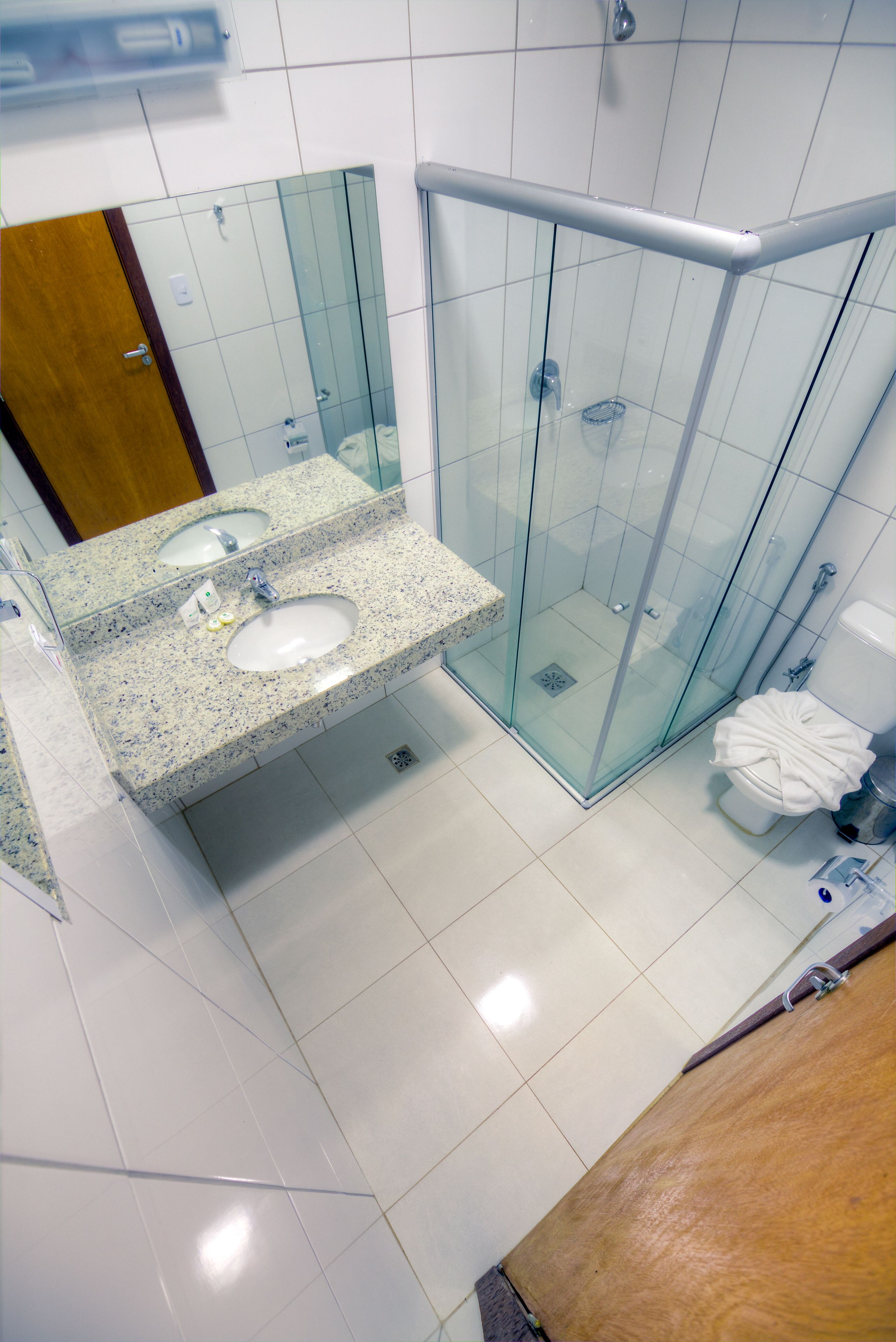 A modern bathroom with a glass-enclosed shower, a granite countertop sink, and a wooden vanity.