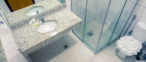 A modern bathroom with a glass-enclosed shower, a granite countertop sink, and a wooden vanity.