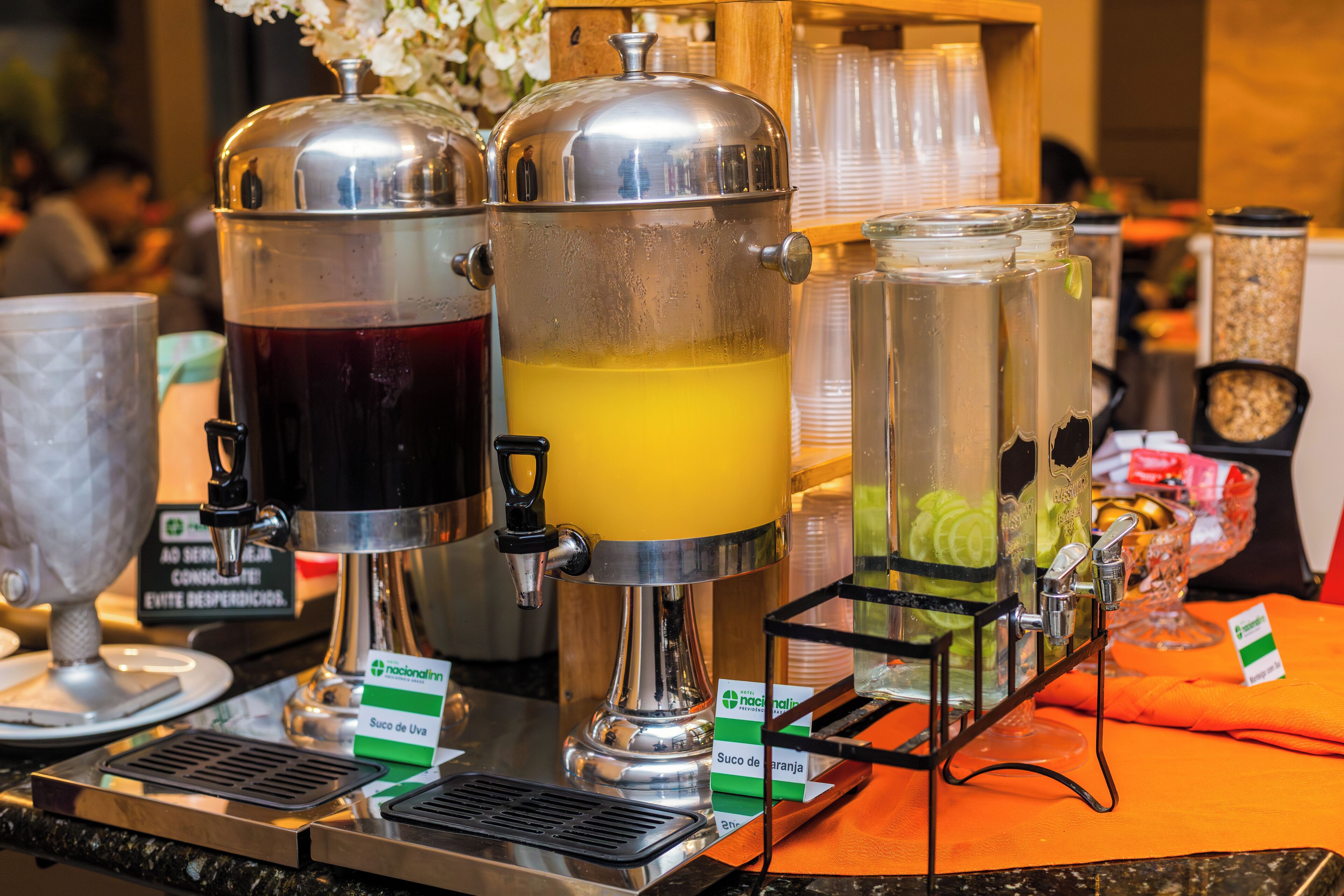 A beverage station with multiple dispensers and a clock in the background.