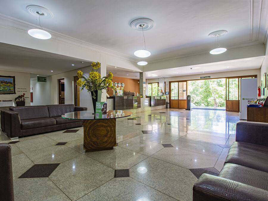 A spacious lobby with a modern design, featuring a central coffee table, sofas, and a reception desk.